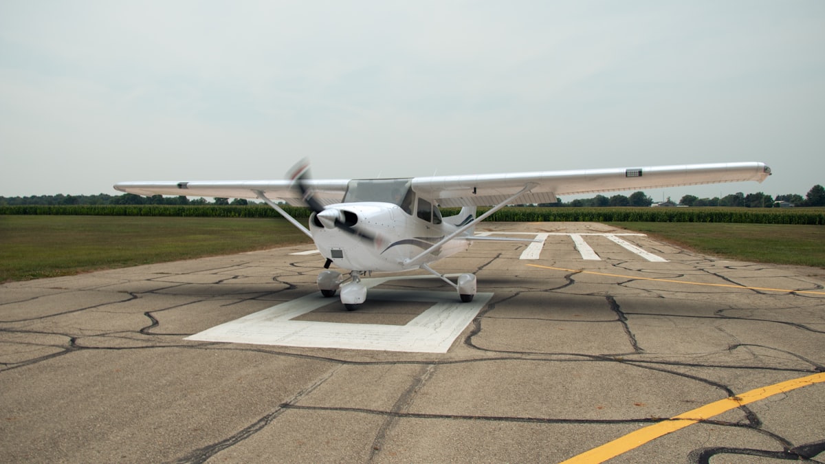 Small aircraft on a runway with a wind sock blowing sideways