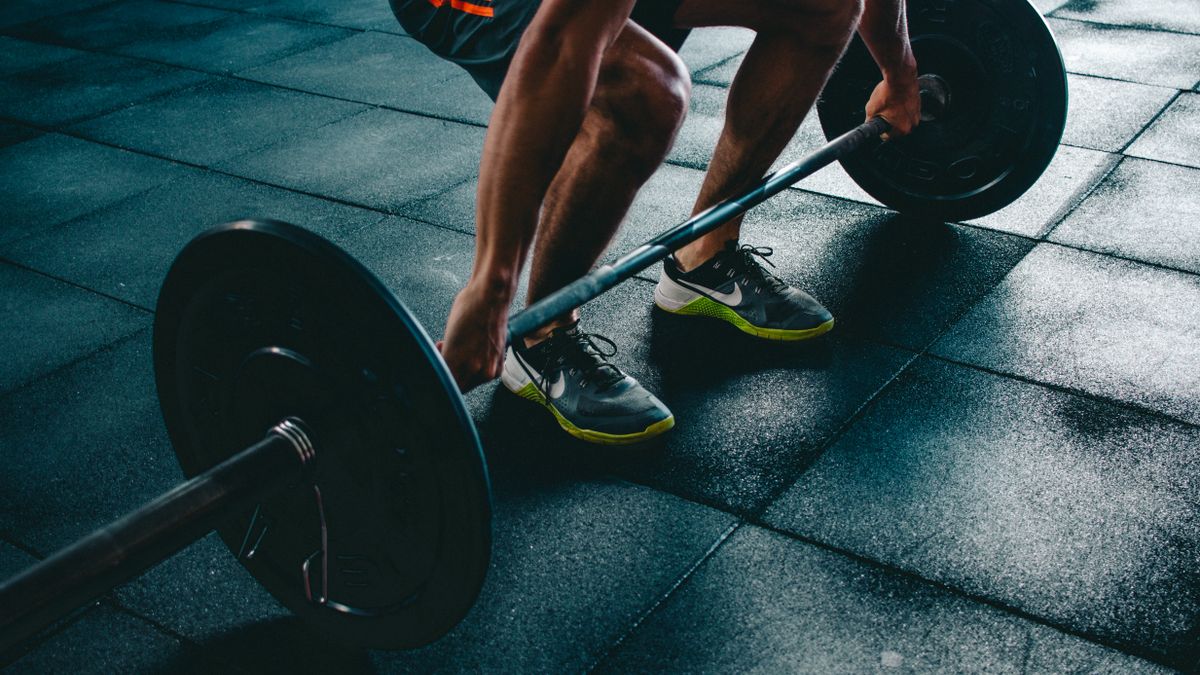 Powerlifter mid-deadlift with a loaded barbell in a gym