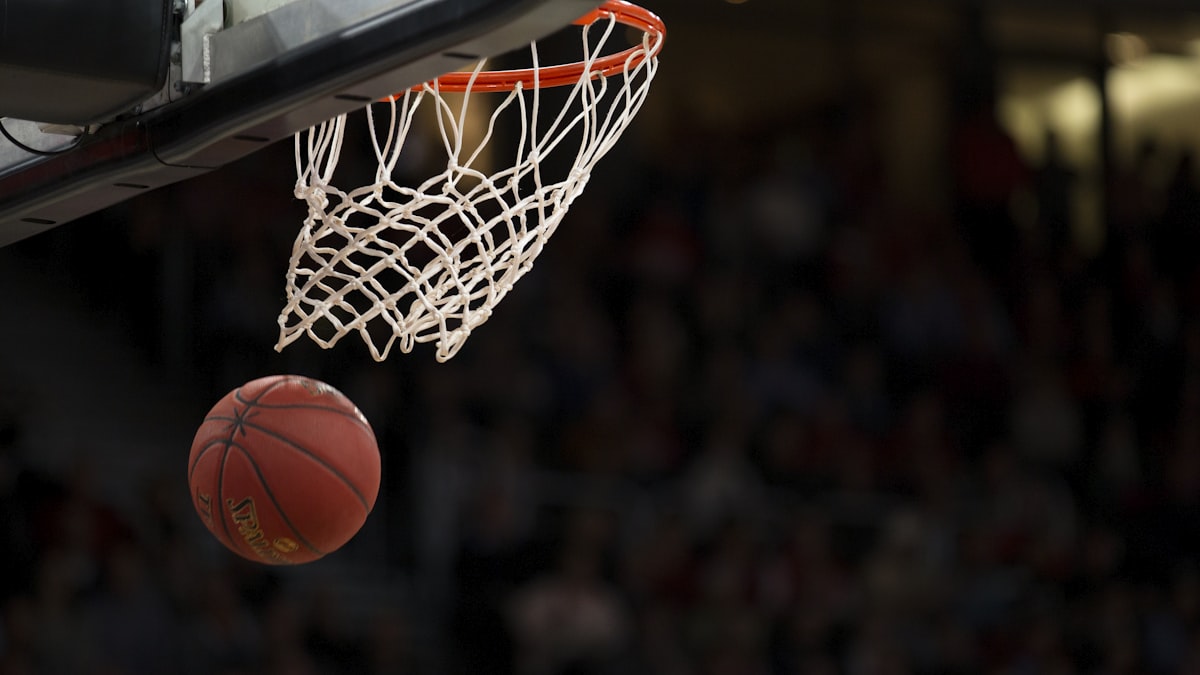 Basketball player dunking over a defender in a gym
