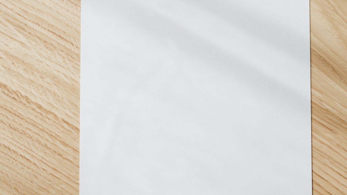 A blank white sheet of paper on a wooden table