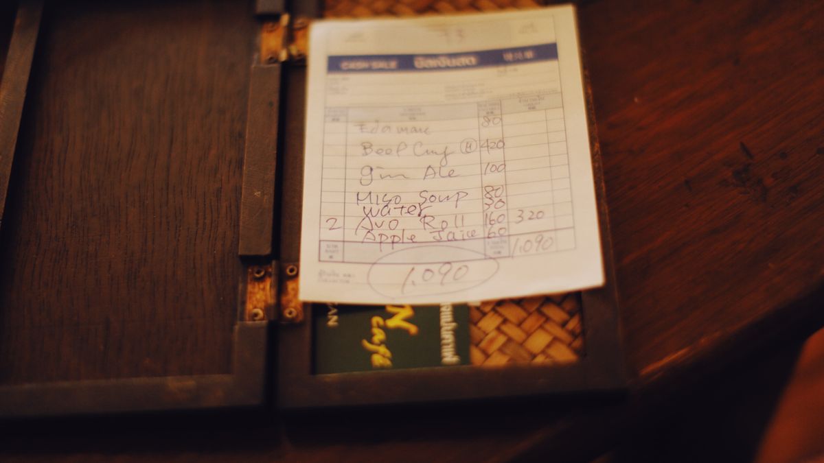 A restaurant bill with cash and a calculator