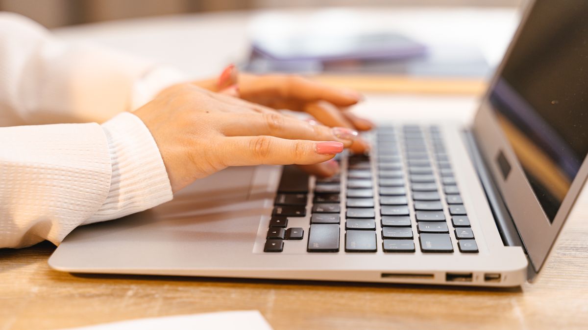 A writer typing on a laptop with text on screen